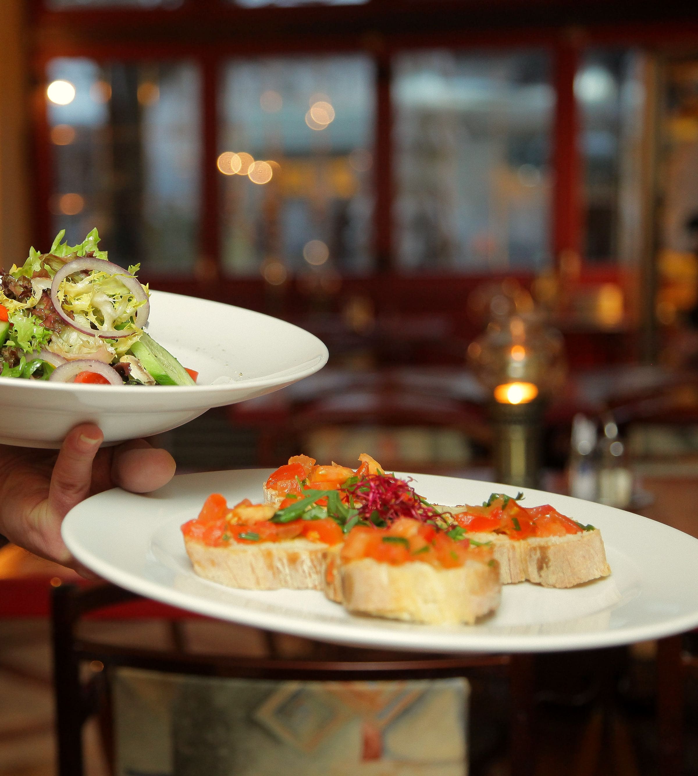 Zwei Teller werden serviert: frischer Salat und Bruschetta mit Tomaten