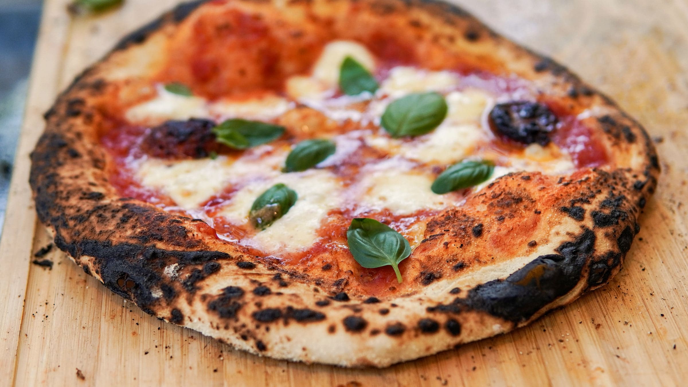 Pizza mit Mozzarella und Basilikum auf einem Holzbrett
